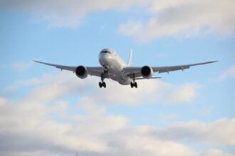 Passenger airplane approaching for landing against a backdrop of blue sky and clouds.