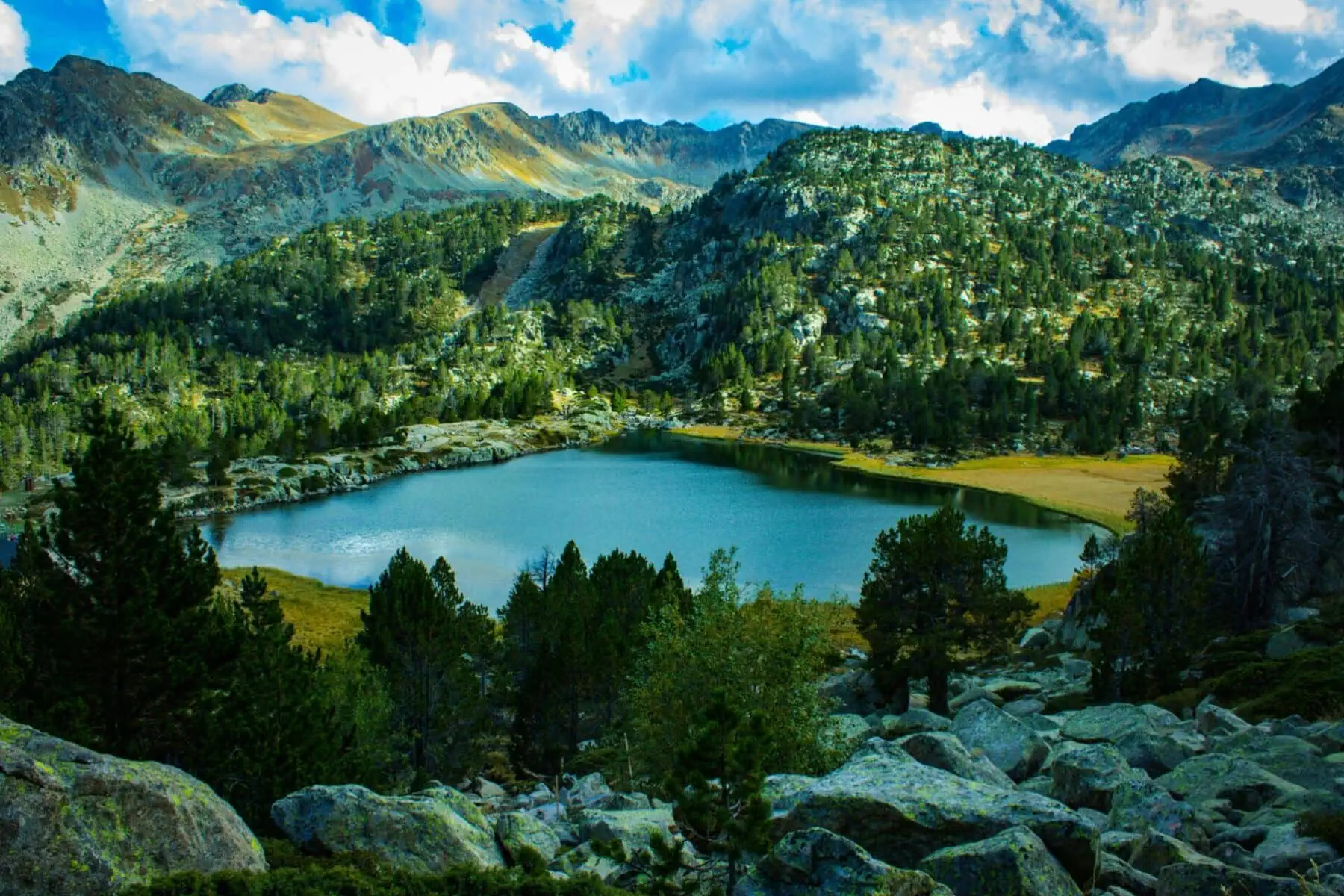 Mountain lake surrounded by rocky peaks and pine trees in Andorra