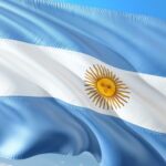 The Argentine flag with light blue and white horizontal stripes and a yellow sun with a face in the center.