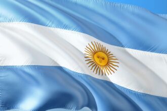 The Argentine flag with light blue and white horizontal stripes and a yellow sun with a face in the center.