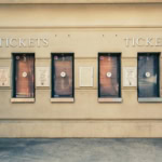 Row of closed ticket booths at an attraction venue, with numbered windows and accessibility signage