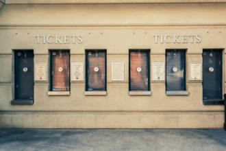 Row of closed ticket booths at an attraction venue, with numbered windows and accessibility signage