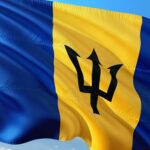 Barbados flag with blue background and yellow stripe containing black trident symbol waving against sky