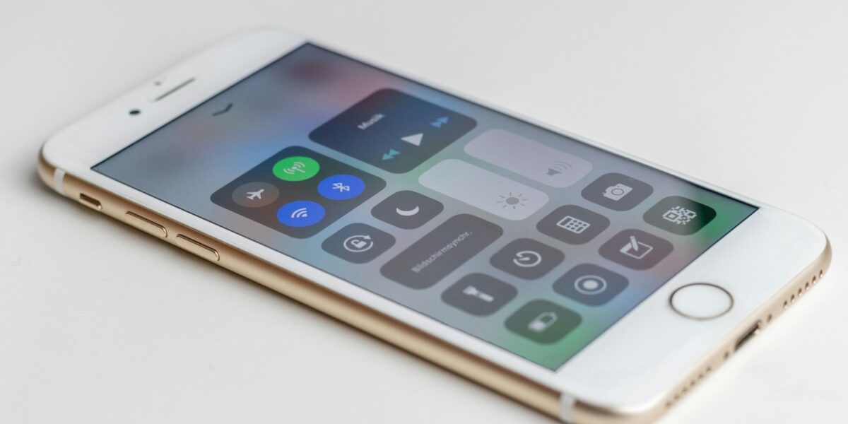 iPhone displaying iOS Control Center with connectivity toggles including Bluetooth, Wi-Fi, cellular, and airplane mode icons visible on screen