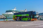 FlixBus double-decker coach boarding passengers near a cruise ship dock in Venice, Italy.