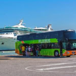 FlixBus double-decker coach boarding passengers near a cruise ship dock in Venice, Italy.