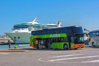 FlixBus double-decker coach boarding passengers near a cruise ship dock in Venice, Italy.