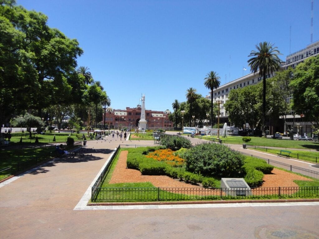 Plaza de Mayo in Buenos Aires with gardens, palm trees, and the pink Casa Rosada in the background.