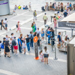 Travellers queue to buy attraction tickets at a popular tourist destination using city passes and mobile ticket apps.
