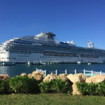 Large white cruise ship docked at a Caribbean port under clear blue skies