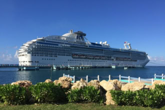 Large white cruise ship docked at a Caribbean port under clear blue skies