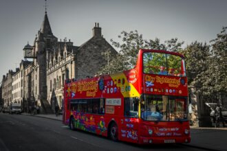 City Sightseeing tour bus driving past historic buildings in Edinburgh, Scotland