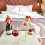 Luxury hotel room with champagne, wine, and desserts on a table – perfect for a romantic getaway booked via top hotel booking apps.