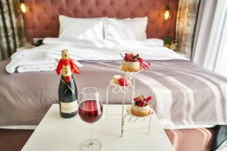 Luxury hotel room with champagne, wine, and desserts on a table โ perfect for a romantic getaway booked via top hotel booking apps.
