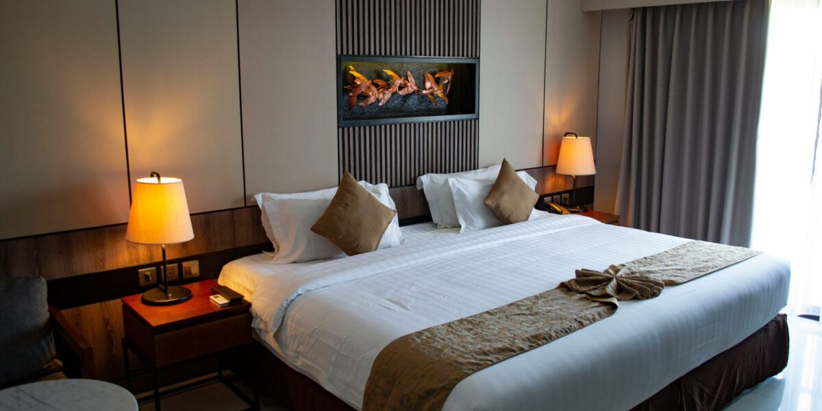 Modern hotel room with a large double bed, bedside lamps, and contemporary decor, ideal for illustrating global hotel group apps.