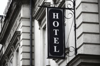 Black and white vertical hotel sign mounted on a historic stone building facade