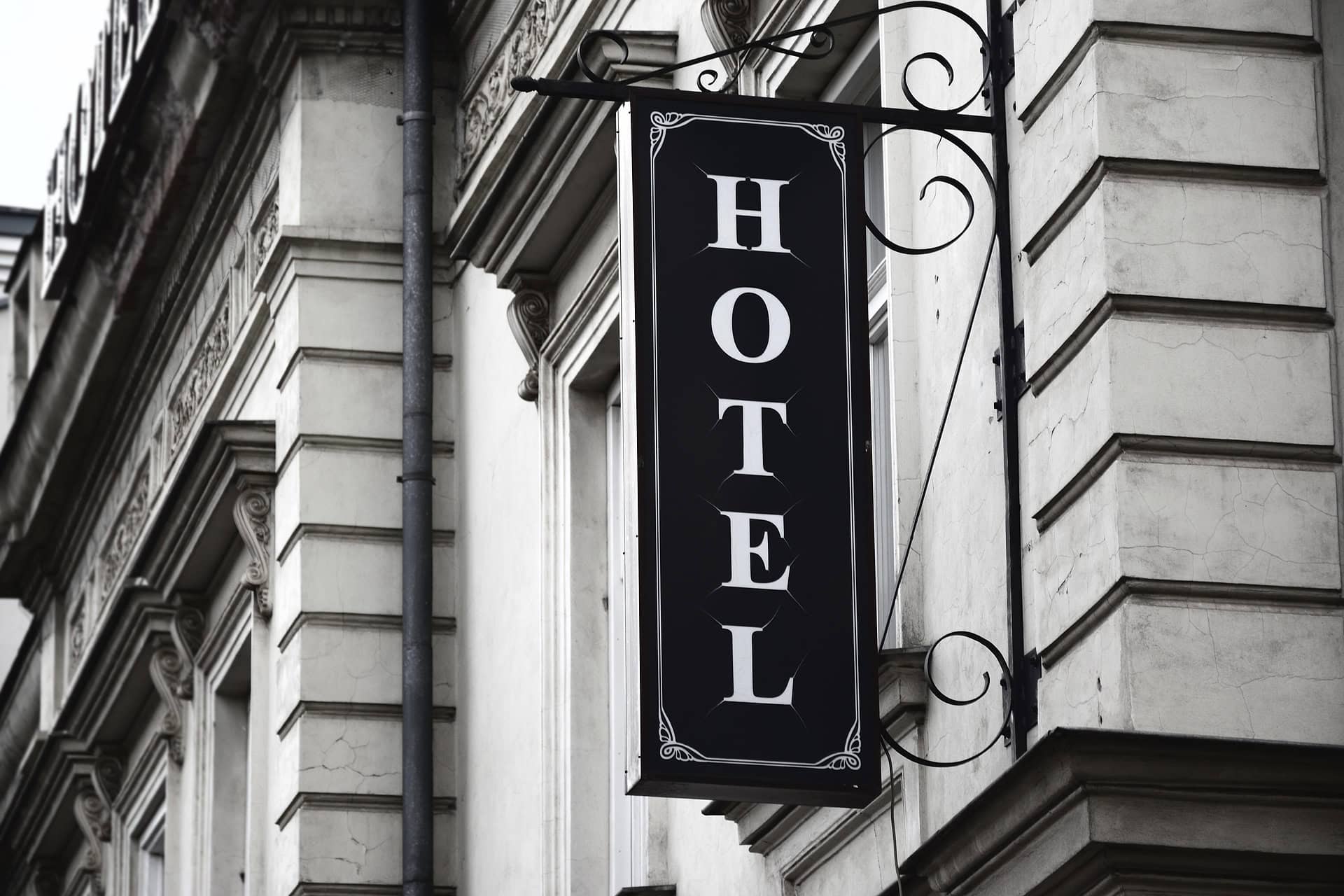 Black and white vertical hotel sign mounted on a historic stone building facade