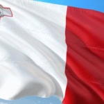Flag of Malta waving against a blue sky