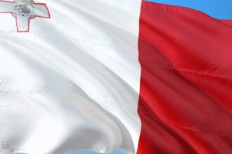 Flag of Malta waving against a blue sky