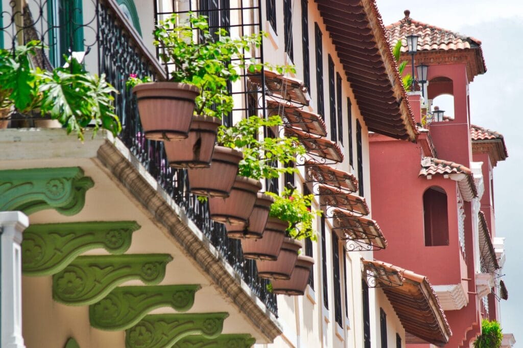 Colorful colonial-style buildings in Panama with ornate balconies and lush potted plants.