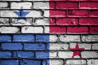Panama flag design painted on weathered brick wall with blue, white, and red sections and stars