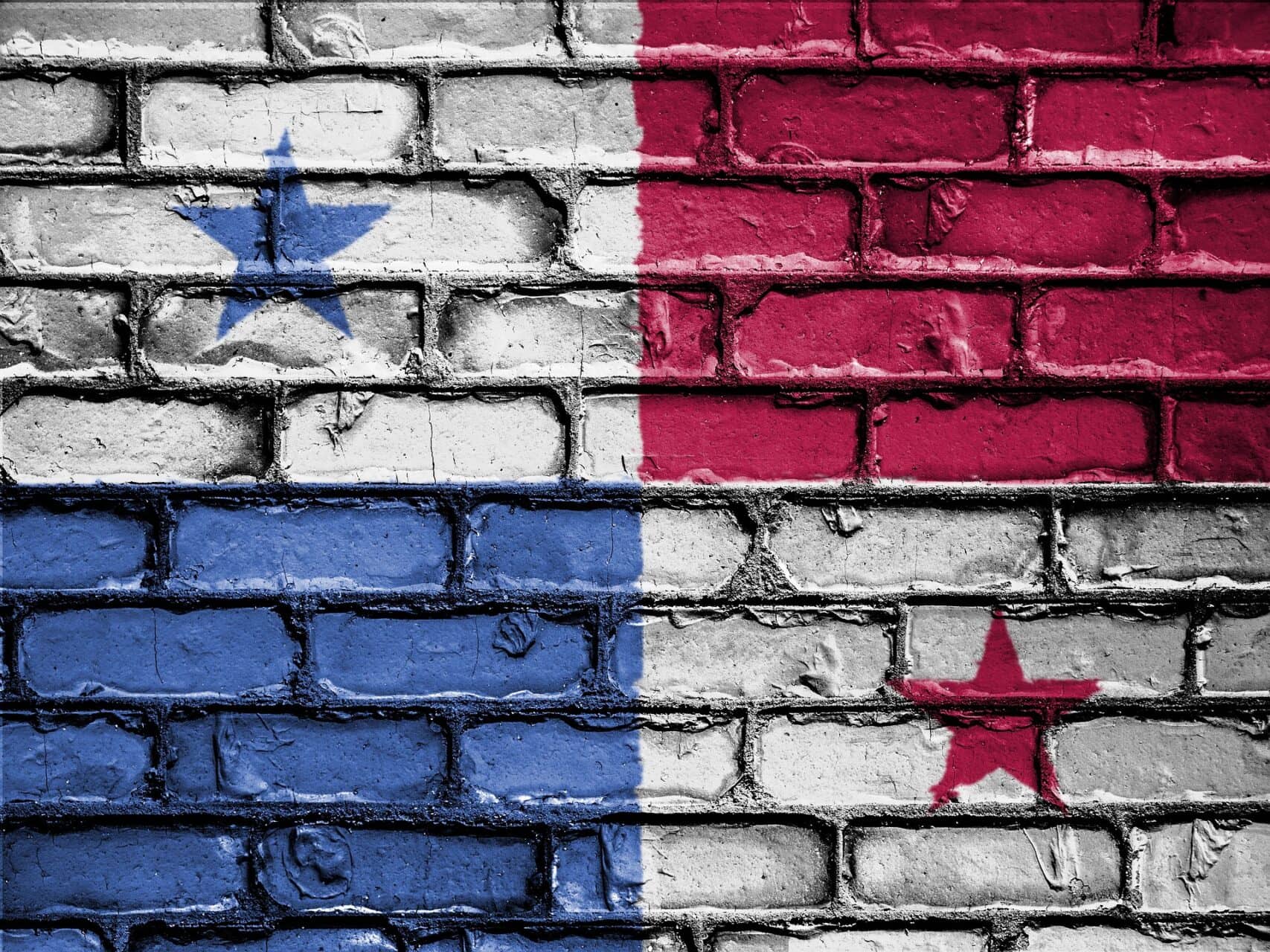 Panama flag design painted on weathered brick wall with blue, white, and red sections and stars