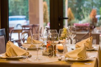 Fine dining restaurant table with folded napkins, wine glasses, candles, and flowers – perfect for a restaurant table booking apps guide.
