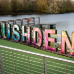 Colorful “Rushden” sign at Rushden Lakes beside the water