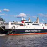 White and red Steam Packet ferry departing Liverpool waterfront with city skyline behind