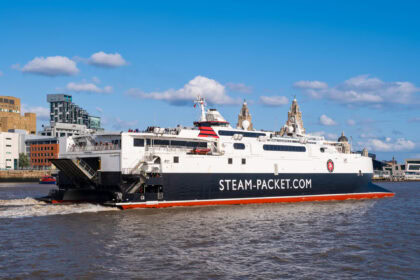 White and red Steam Packet ferry departing Liverpool waterfront with city skyline behind