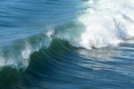 Close-up of a powerful ocean wave curling and breaking, illustrating the importance of tide time apps for coastal activities.