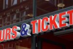 Close-up of a "Tours & Tickets" sign outside a travel booking office, representing tour booking and attraction ticket services.