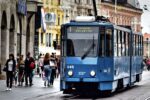 Blue tram passing through a busy street in Zagreb, Croatia, with pedestrians and historic buildings in the background