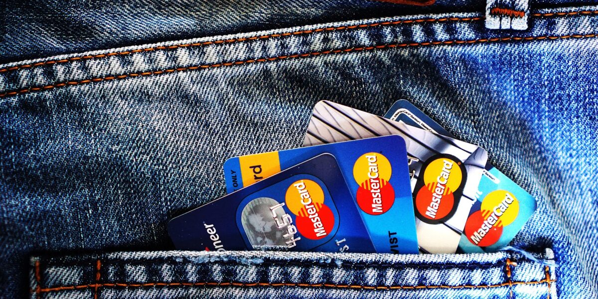Multiple Mastercard credit and debit cards fanned out in a denim jeans pocket, showing blue and multicolored card designs
