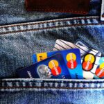 Multiple Mastercard credit and debit cards fanned out in a denim jeans pocket, showing blue and multicolored card designs