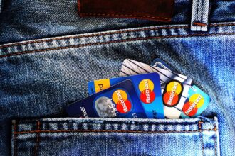 Multiple Mastercard credit and debit cards fanned out in a denim jeans pocket, showing blue and multicolored card designs