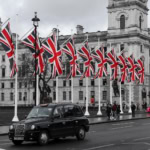 Black London taxi driving past Union Flags, a quintessential British scene for a United Kingdom travel guide.