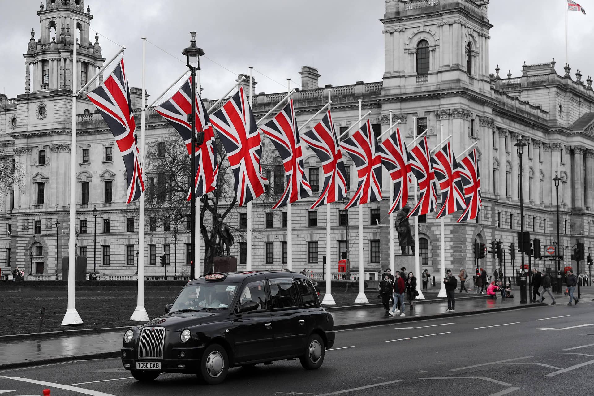 Black London taxi driving past Union Flags, a quintessential British scene for a United Kingdom travel guide.