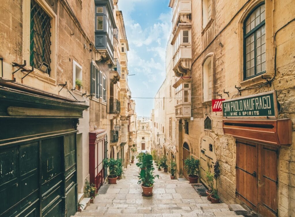 Narrow stone street with traditional Maltese balconies in Valletta, Malta