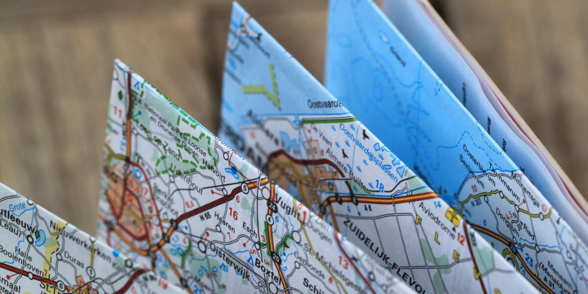 Folded paper maps displaying detailed road networks, place names, and numbered routes with Dutch location names visible