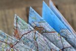 Folded paper maps displaying detailed road networks, place names, and numbered routes with Dutch location names visible