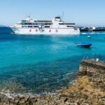 Ferry from Armas sailing in the Balearic Islands, Spain with clear turquoise waters and small boats nearby