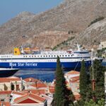 Blue Star Ferries ship arriving at Symi Island harbour with hillside houses in the background