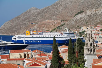 Blue Star Ferries ship arriving at Symi Island harbour with hillside houses in the background
