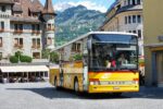 Bright yellow Swiss PostBus in a mountain town square, ideal for illustrating intercity and rural coach travel featured in the Busbud app guide.