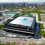 Aerial view of Co-op Live Manchester arena next to the Etihad Campus with the city skyline in the background.