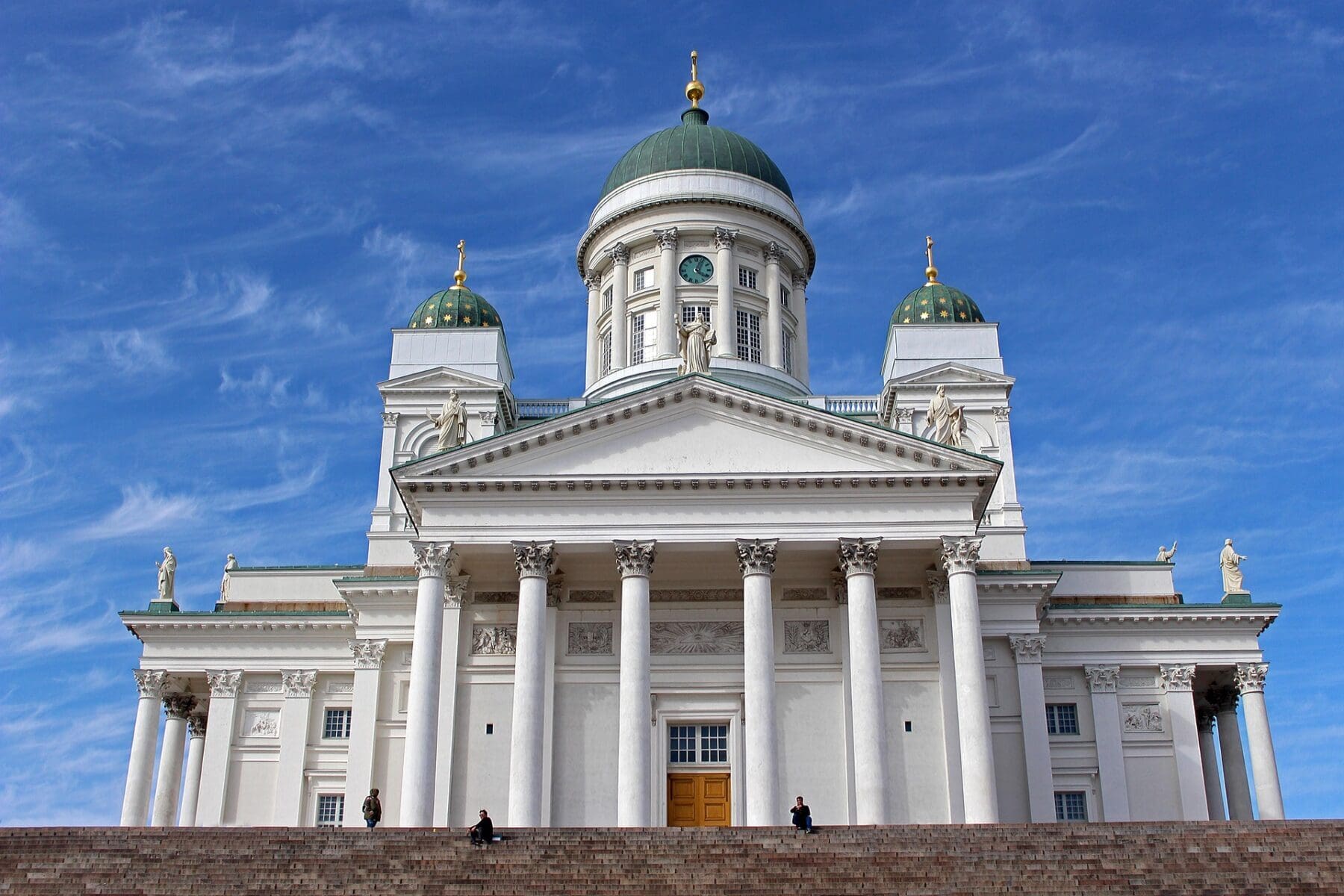 White Helsinki Cathedral with green domes against a vivid blue sky