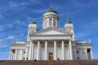 White Helsinki Cathedral with green domes against a vivid blue sky