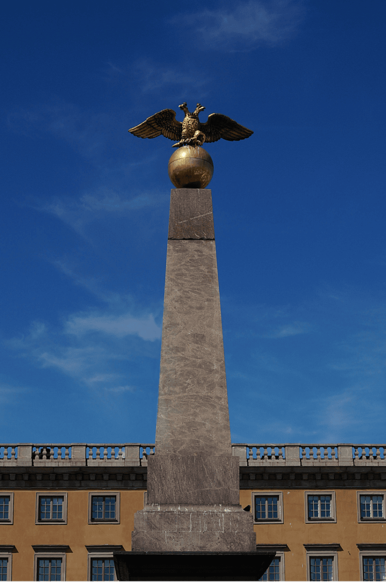 Tsarina’s Stone monument topped with a golden double-headed eagle against a clear blue sky in Helsinki, Finland.