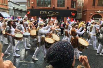 Drummers in colourful costumes leading the Manchester Day parade along Deansgate.